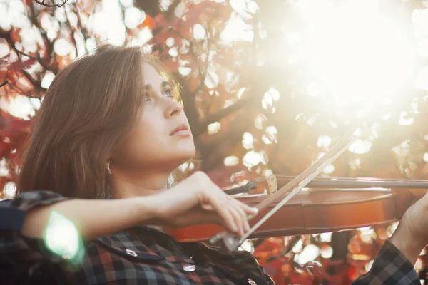붉은 잎을 배경으로 바이올린을 연주하는 낭만적 인 소녀의 가을 초상화, 자연에 대한 공연, 취미와 미술의 개념 — 스톡 사진