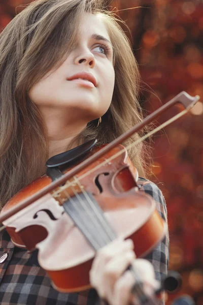 가을에 아름다운 여성 이 빨간 나뭇잎을 배경으로 바이올린을 연주하는 것을 즐기고, 자연에 대한 예술에 종사하는 로맨틱 한 소녀, 취미와 음악 생활에 대한 개념 — 스톡 사진