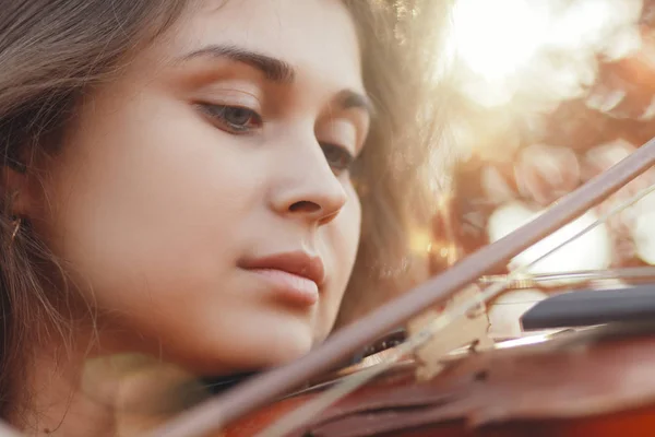 Cara de mujer hermosa con violín bajo su barbilla vista inferior, chica romántica dedicada al arte, actuación en la naturaleza de otoño, concepto de hobby y música — Foto de Stock