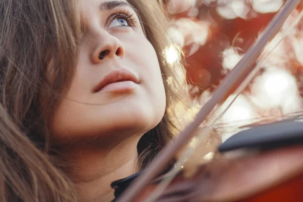 Cara de mujer hermosa con violín bajo su barbilla vista inferior, chica romántica dedicada al arte, actuación en la naturaleza de otoño, concepto de hobby y música — Foto de Stock