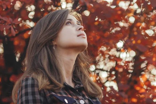 Perfil de una hermosa mujer joven mirando hacia arriba con gratitud, chica caminando a través de la naturaleza de otoño en un parque — Foto de Stock