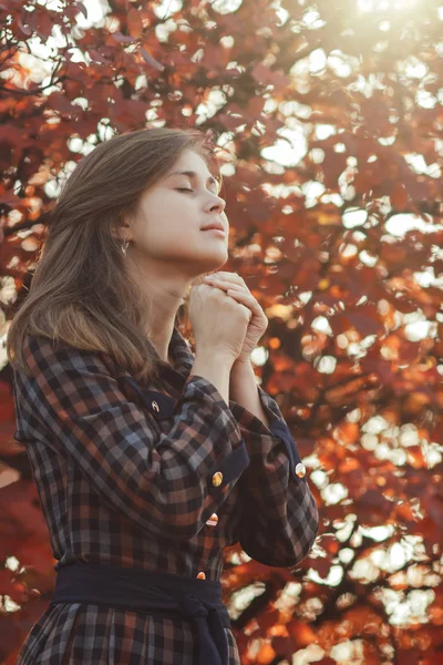 Portrait d'une jeune femme priant dans la nature, la jeune fille remercie Dieu avec ses mains pliées à son menton, une conversation avec le Créateur, le concept de religion — Photo