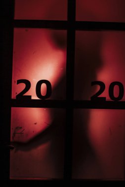 Kapı kolunun silüeti, üzerinde kırmızı bir ışık ve tarihi olan kapı kolunu açmak, yeni yılın klişesini yıkmak, 2020 korku türüne girmek.