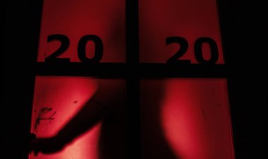 Kapı kolunun silüeti, üzerinde kırmızı bir ışık ve tarihi olan kapı kolunu açmak, yeni yılın klişesini yıkmak, 2020 korku türüne girmek.