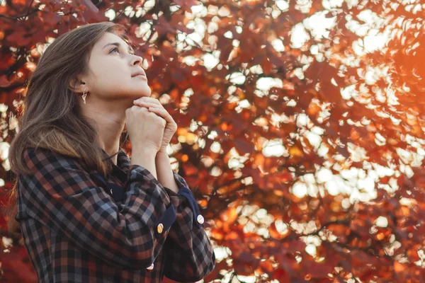 Porträt einer jungen Frau, die in der Natur betet, das Mädchen dankt Gott mit gefalteten Händen am Kinn, ein Gespräch mit dem Schöpfer, das Konzept der Religion — Stockfoto