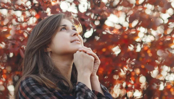 Portrait d'une jeune femme priant dans la nature, la jeune fille remercie Dieu avec ses mains pliées à son menton, une conversation avec le Créateur, le concept de religion — Photo