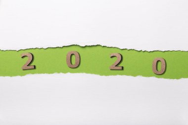 2020 tarihli ahşap figür yırtık beyaz karton şeridinin altında, yeşil yırtık kağıt deliğinde numaralar, yeni yıl konsepti, takvim kapağı tasarımı