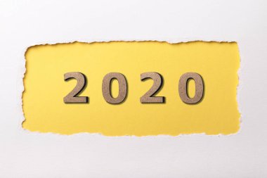 Yırtık karton sarı delikte 2020 tarihinin tahta figürlü beyaz arkaplan, yeni yıl konsepti, takvim kapağı tasarımı