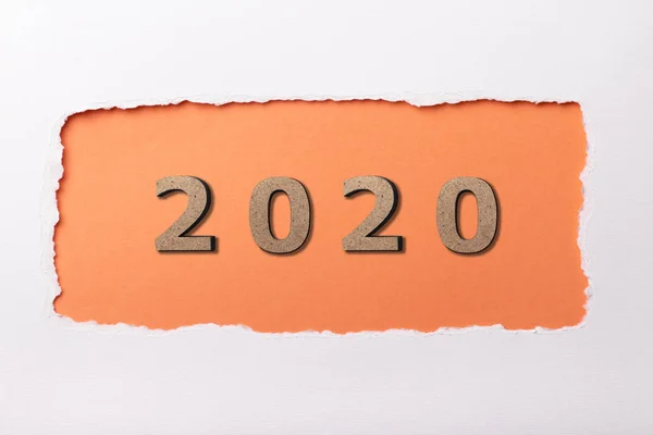 Fondo blanco con figura de madera de la fecha 2020 en agujero naranja de cartón desgarrado, concepto de año nuevo, diseño de la cubierta del calendario — Foto de Stock