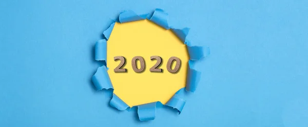 Sfondo colorato con figura in legno della data 2020 in buco giallo di cartone strappato blu, concetto di anno nuovo, copertina del calendario — Foto Stock