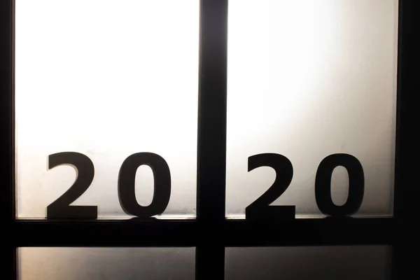 Silhouette date 2020 in piedi sulla porta contro un Strangolebacklight, concetto di nuovo anno e la paura del futuro — Foto Stock