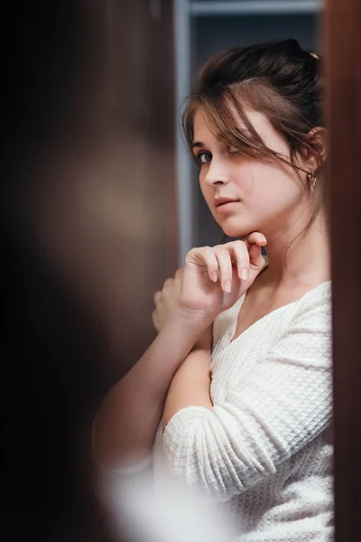 Retrato de menina bonita com a mão sob o queixo, jovem com em casa interior olhando no espelho e posando, conceito de beleza feminina — Fotografia de Stock