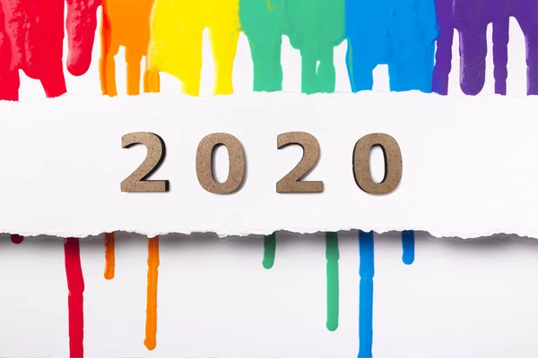 Malované abstraktní pozadí s dřevěnými figurami datováno 2020, novoroční koncept, design obálky kalendáře s tekoucí pestrobarevnou barvou — Stock fotografie