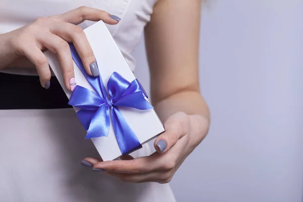 Mujer manos apertura caja de regalo en un fondo de estudio, hembra desatando lazo azul, vacaciones concepto — Foto de Stock