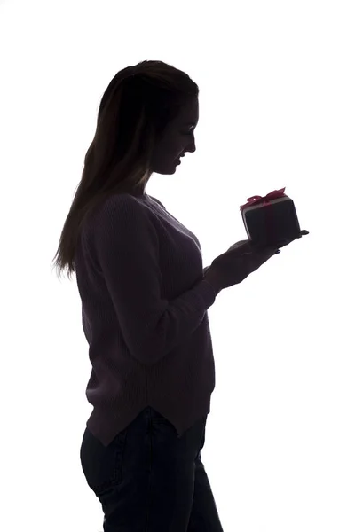 Silhouette of a young woman with a gift in hands, girl with a box with a bow on a white isolated background,concept of holidays — 스톡 사진