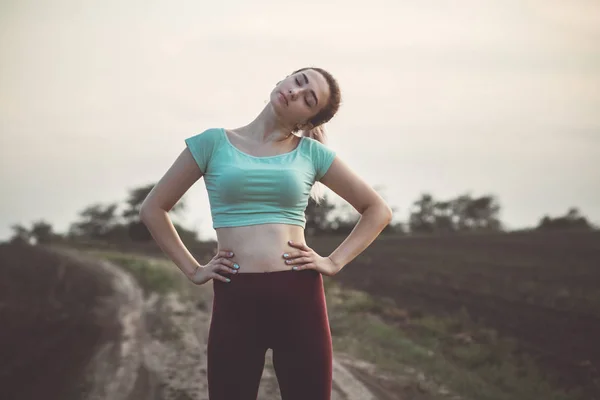 スポーツ女性の運動や曇りの空を背景に筋肉を伸ばす 屋外でフィットネストレーニングに従事する女の子 コンセプト健康的なライフスタイル — ストック写真