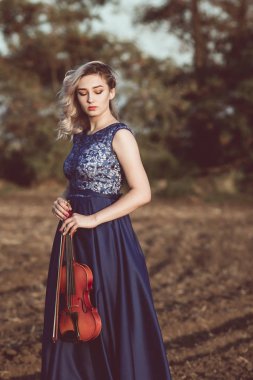 Çenesinin altında keman olan güzel bir kızın yüzü, yalnızlık, konsept müzik ve duygular üzerine müzik aleti çalan genç bir kadın.