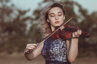 Çenesinin altında keman olan güzel bir kızın yüzü, yalnızlık, konsept müzik ve duygular üzerine müzik aleti çalan genç bir kadın.