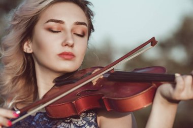 Çenesinin altında keman olan güzel bir kızın yüzü, yalnızlık, konsept müzik ve duygular üzerine müzik aleti çalan genç bir kadın.