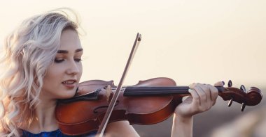 Çenesinin altında keman olan güzel bir kızın yüzü, yalnızlık, konsept müzik ve duygular üzerine müzik aleti çalan genç bir kadın.
