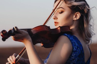 Çenesinin altında keman olan güzel bir kızın yüzü, yalnızlık, konsept müzik ve duygular üzerine müzik aleti çalan genç bir kadın.