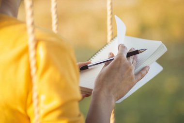 Salıncakta sallanan güzel bir kız, elinde defter ve kalemle doğada duyguların günlüğünü tutuyor, bir kadın besteleyip yazıyor, romantik bir ruh hali içinde.