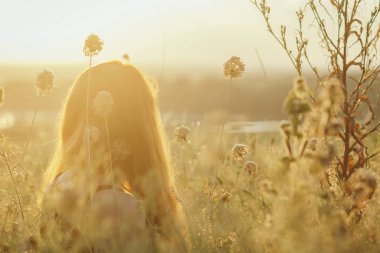 kurutulmuş çiçekler arasında bir alanda yerde oturan kırmızı saçlı kız baş ve gün batımında doğa sahiptir, genç kadın rahatlatıcı, dinlenme kavramı, sağlık, uyum, yaşam tarzı