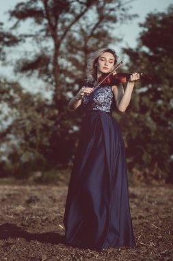 Çenesinin altında keman olan güzel bir kızın yüzü, yalnızlık, konsept müzik ve duygular üzerine müzik aleti çalan genç bir kadın.