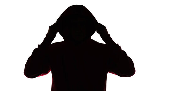 dark male silhouette in casual sportswear with a hood, figure of a guy hiding his face, concept of privacy and confidentiality
