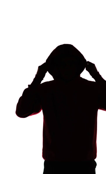 dark male silhouette in casual sportswear with a hood, figure of a guy hiding his face, concept of privacy and confidentiality