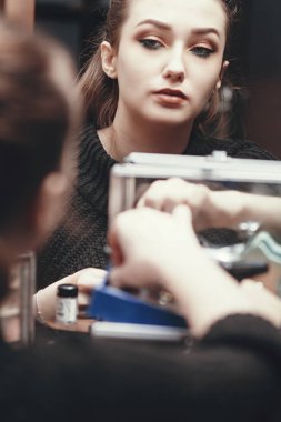 Aynada aynada makyaj yapan güzel bir kızın yansıması. Evdeki soyunma odasında makyaj yapıyor. Kendine bakan şık bir genç kadın.