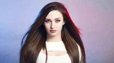 Stüdyo arka planında uzun saçlı, kendine güvenen güzel bir kızın portresi, düzgün görünümlü genç bir kadın, manken.