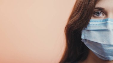 Ciddi genç kadın yüzünün yarısı renkli stüdyo geçmişine koruyucu tıbbi maske takıyor, hastalık ve karantina önlemleri kavramı, Avrupa 'da yayılan koronavirüs