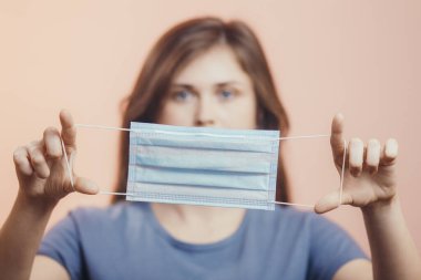 Renkli stüdyo geçmişi, karantina önlemleri ve hayat kurtaran konsept üzerinde açık bir tıbbi grip maskesi gösteren genç kadın portresi