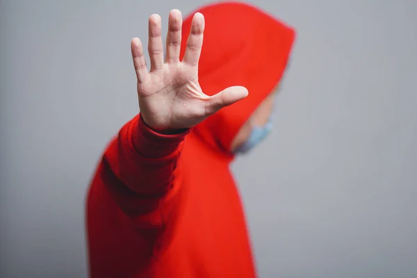 Jovem Uma Camisola Vermelha Máscara Protetora Médica Mostra Gesto Parada — Fotografia de Stock