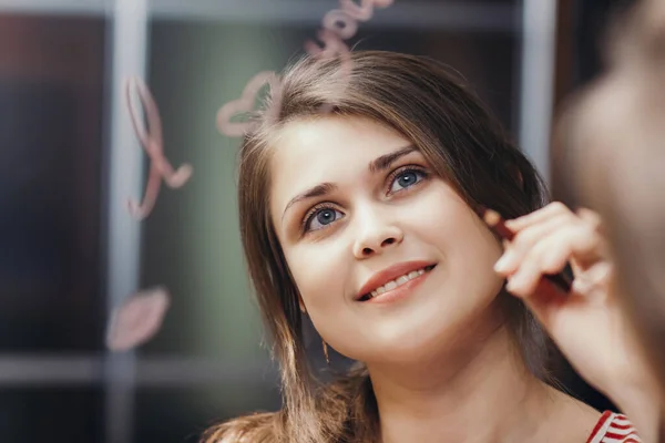 reflection of young woman writing with cosmetic pencil words \