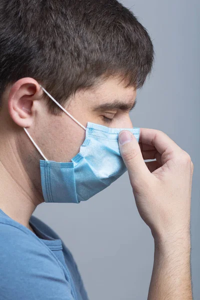 upset young doctor in protective medical mask thinking about problem on gray studio background, concept medicine and health,exhaustion at work