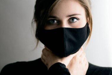 Siyah maskeli, boynunu sıkan güzel bir kadının portre yüzü 2020 'de karantina ve salgın altında yaşamak insanı boğuyor. Tehlike kavramı.