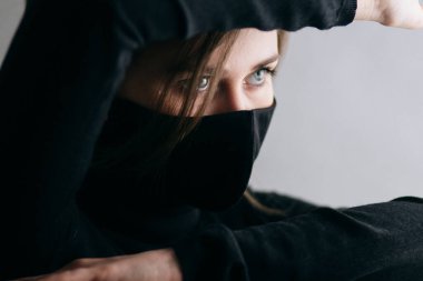 Siyah stil bir maske takmış genç güzel bir kadının portresi, yüzünü elleriyle kapatıyor, tehlikeyi kavrayamıyorum, savaşmaya hazır ajan kız.