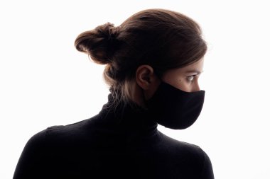 Stüdyonun arka planında siyah maskeli genç bir kadının siluet profili, ajan gibi görünen bir kız, konsept güvenlik.