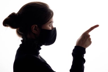 silhouette profile of young woman in protective mask pokes a finger at an adversary on white studio background, girl blames, concept justice clipart