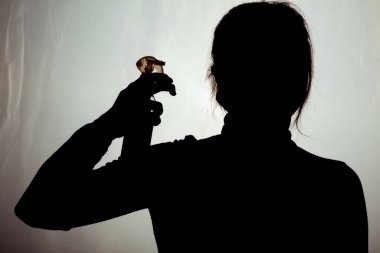 Koruyucu maskeli bir kadın yeşil arka planda kafasına dezenfektan spreyi sıkarak insanları öldürüyor, karantina önlemleri...