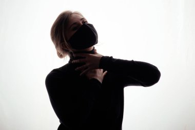 Siyah maskeli genç bir kadın boynunu sıkıyor. 2020 'de karantina altında ve salgın hastalık bir insanı boğuyor. Tehlike kavramı.