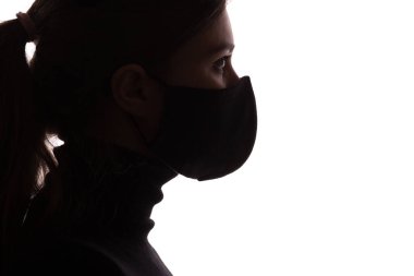 Stüdyonun arka planında koruyucu maskeli genç bir kadının siluet profili, ajan gibi görünen bir kız, konsept güvenlik
