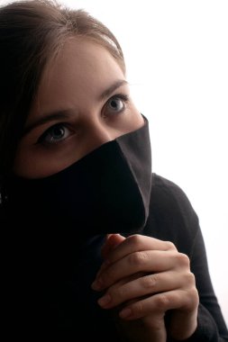 Stüdyo arka planında koruyucu maskeli genç bir kadın silueti başını kaldırdı, sağlık ve güvenlik kavramı, salgın sorunu.
