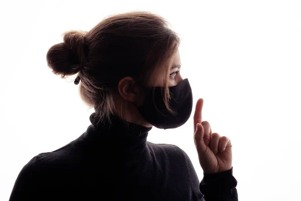 戴防护面具的年轻女性的轮廓在肮脏的绿色背景上表现出沉默的姿态 手指靠近嘴的女孩嘘 对真相的概念沉默 信息欺骗 — 图库照片