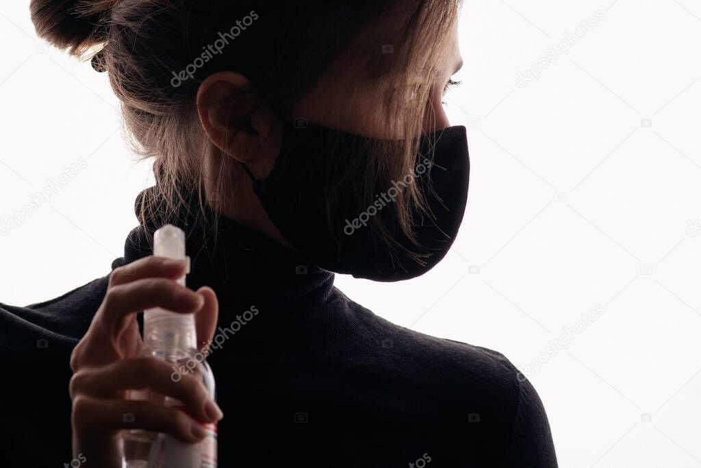 young stelish woman in black mask holding bottle of disinfectant spray, fight against spread of infection, healtht security agent, concept of sterility and hygiene
