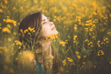 Güzel romantik kız çiçek açan kolza tohumu tarlasında doğanın tadını çıkarıyor, zarif bir kadın yürüyor, güzel bir kadın yüzü, konser mutluluğu, özgürlük, ilham