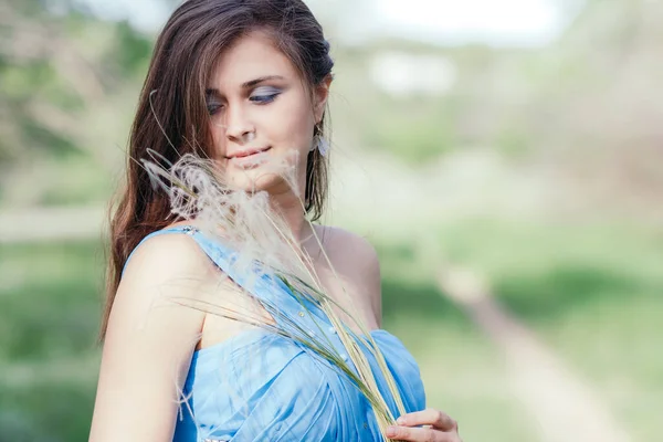 美丽的浪漫女孩 手里拿着蓬松的羽草 年轻优雅的女人的脸 穿着蓝色长裙的新娘 享受大自然 — 图库照片