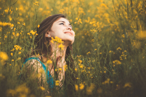 beautiful romantic girl on blooming rapeseed field enjoying nature, young smiling woman walking, pretty female face looking up, concept happiness , inspiration